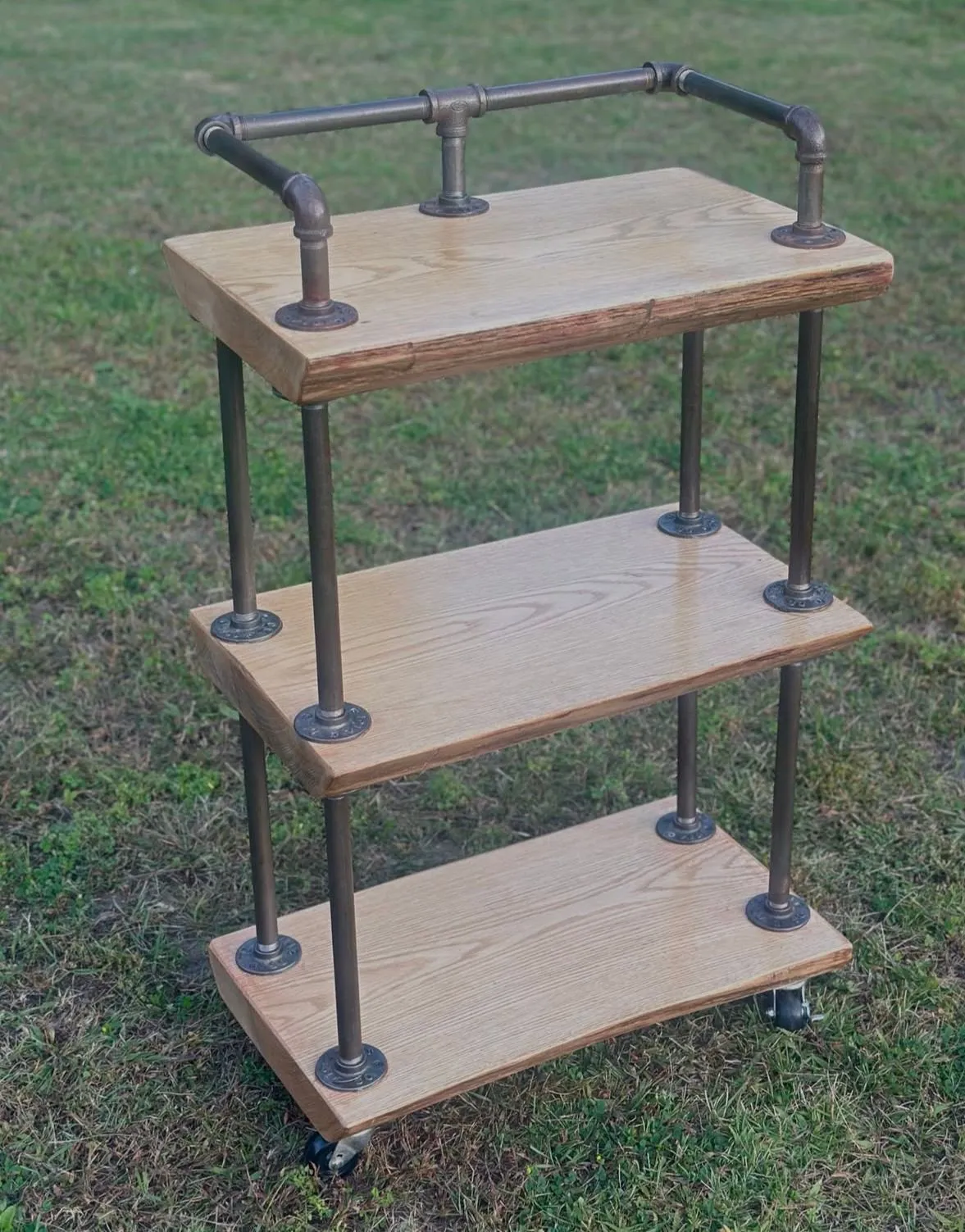 Three-tier oak shelving trolley with a dark steel pipe frame and castors