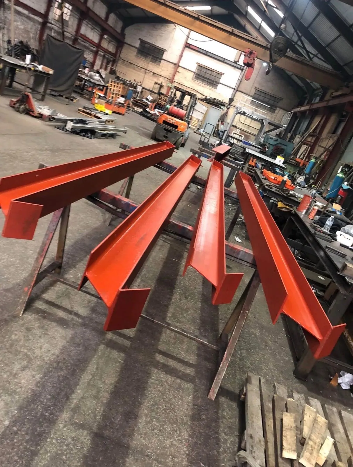 Red-oxide coated structural steel beams staged inside the fabrication workshop